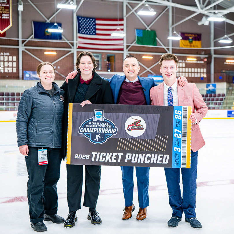 Four people pose on the ice holding a Norwich 2026 NCAA Women's Hockey Championship Ticket Punched sign.