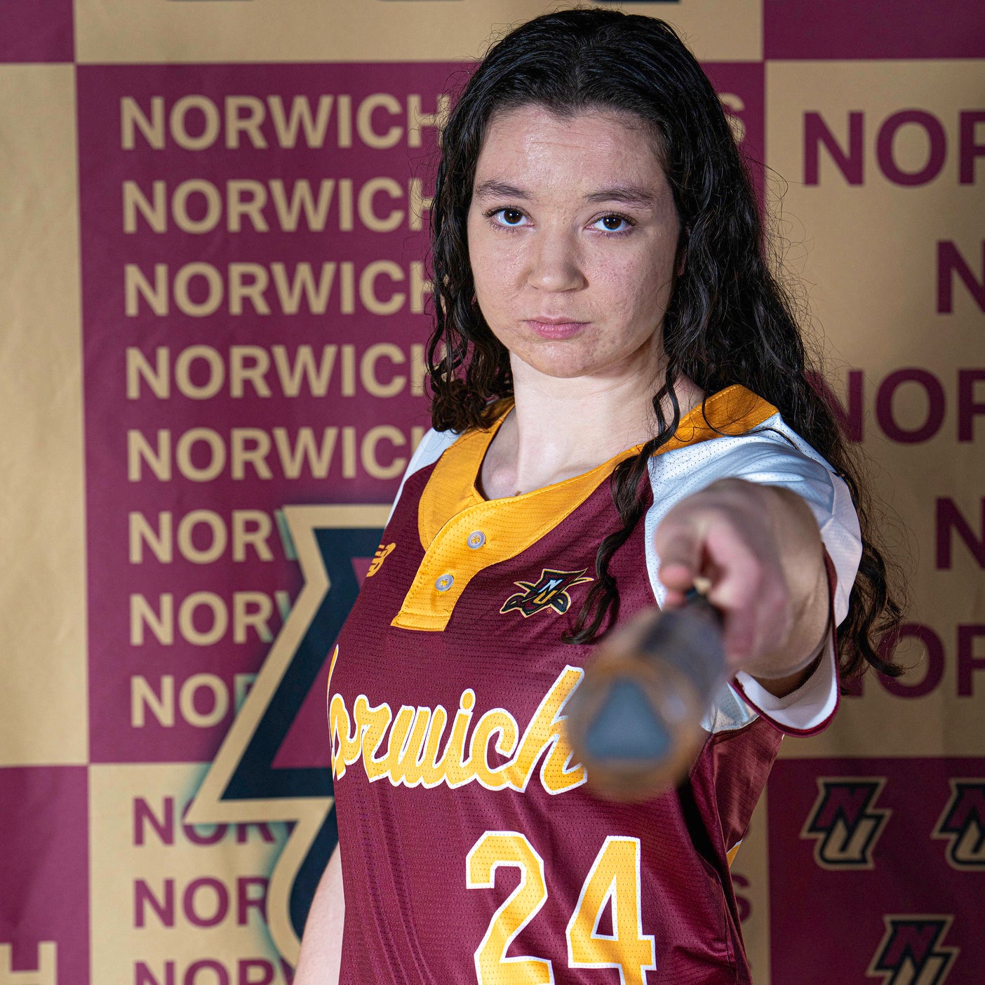Softball player in Norwich jersey #24 points a bat toward the camera.