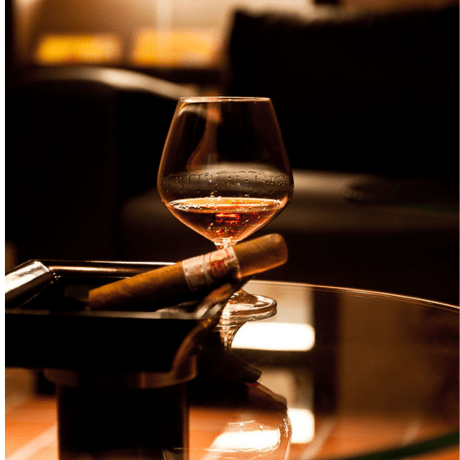 An image of a cigar and a glass of liquor on a table