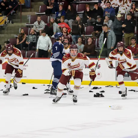 Norwich Mens Hockey cadets skate on the ice after scoring a goal, the ice littered with donated socks