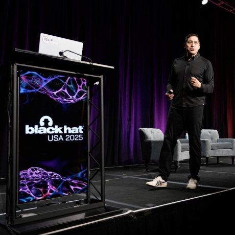 A man walks across a stage as he is giving a conference presentation.