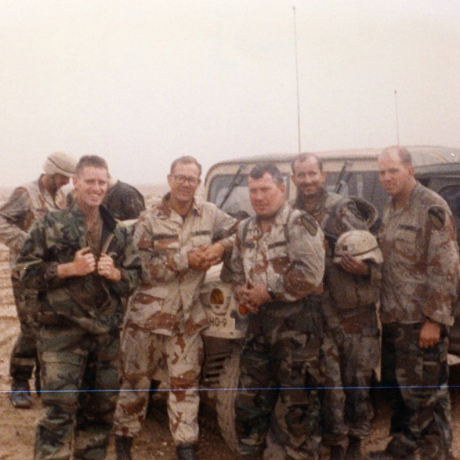 A group of soldiers take a group photo in front of a Humvee during Desert Storm.