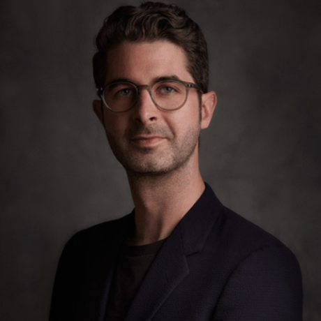 Formal headshot of a man in glasses and black attire.