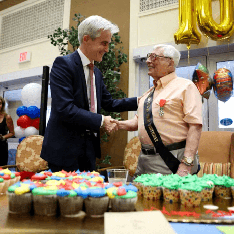 Two people shake hands beside cupcakes and gold number balloons.