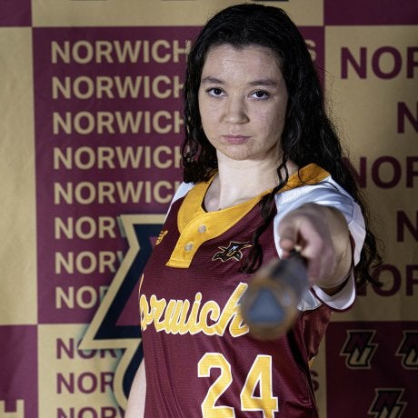 Softball player in Norwich jersey #24 points a bat toward the camera.