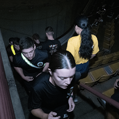 Students walk through dimly lit stadium seating.