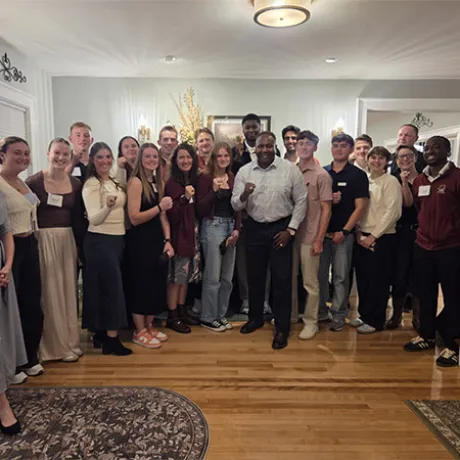 A group of people stands together indoors, with several holding small objects toward the camera.
