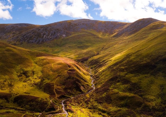 Aerial view of a river valley (center) with hills/mountains rising up above the valley.