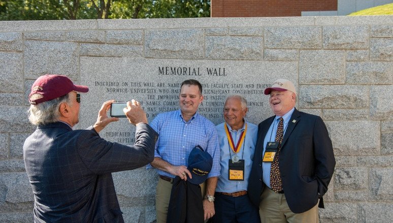 Group of alumni taking photo at Harmon Memorial Wall