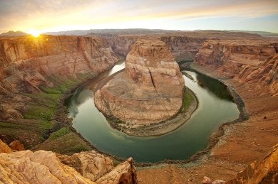 A river - the Colorado River - makes a dramatic horseshoe‑shaped curve around a massive sandstone formation.