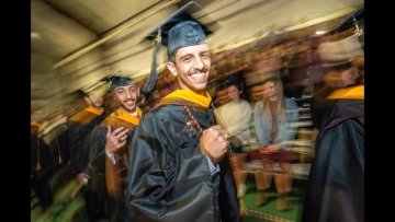 A pair of Saudi students show off their class rings as they march Into the Shapiro Fieldhouse for the 2022 Commencement.