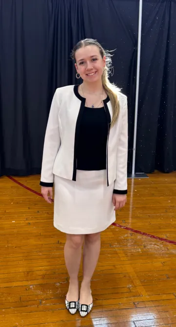 A young woman poses in a white formal dress ensemble. She is wearing formal wear donated to her through Dressing for Success, held Feb. 9-10 at Norwich University.