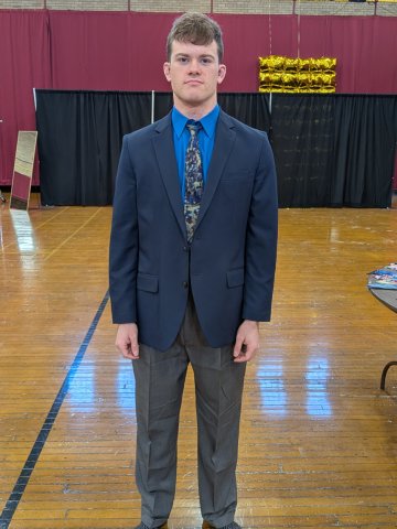 A young man in dark blue suit and gray slacks poses with his arms at his sides. He is donning formal wear donated to him through Dressing for Success, held Feb. 9-10 at Norwich University.