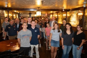 A large crowd gathered for a group photo in a bar / pub.