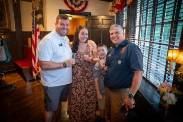 Three adults and a child stand together indoors.